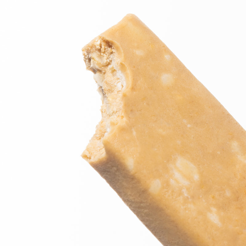 A close-up image of unwrapped and partially bitten White Chocolate Macadamia Cookie Dough bar.