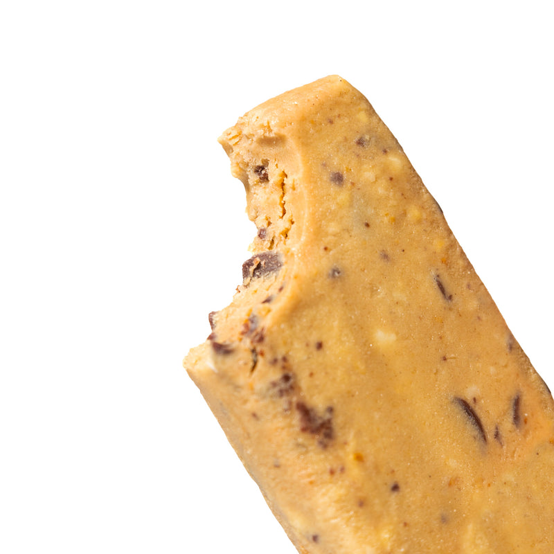 A close-up image of unwrapped and partially bitten chocolate chip cookie dough bar.